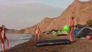 A barefoot girl plays badminton without any clothes on the beach