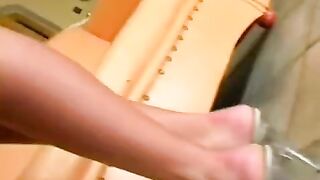 A beauty in a leather chair indulges in solo pleasure