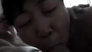 A Chinese woman practices her blowjob skills on her man in a steamy homemade scene