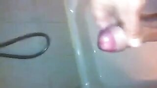 The kid masturbates his dick under a shower jet